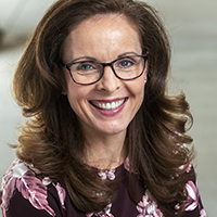Jennifer Victor stands smiling while wearing glasses