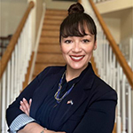 A woman in a black shirt stands inside and smiles