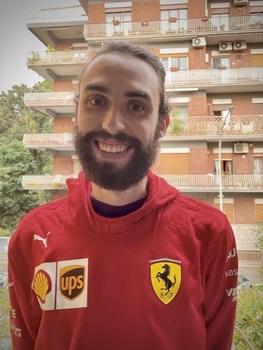 Cato Abbot in a red soccer jersey stands in front of an apartment building in Rome.