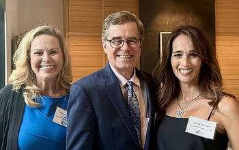 Three people wearing white nametags smile at the camera.