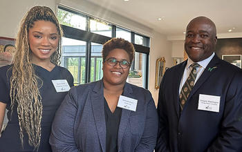 Three people wearing white nametags smile at the camera.