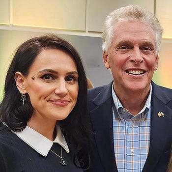 A woman with dark hair and a man with gray hair smile at the camera.