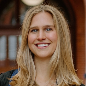 A woman with blonde hair and in a dark top smiles at the camera.